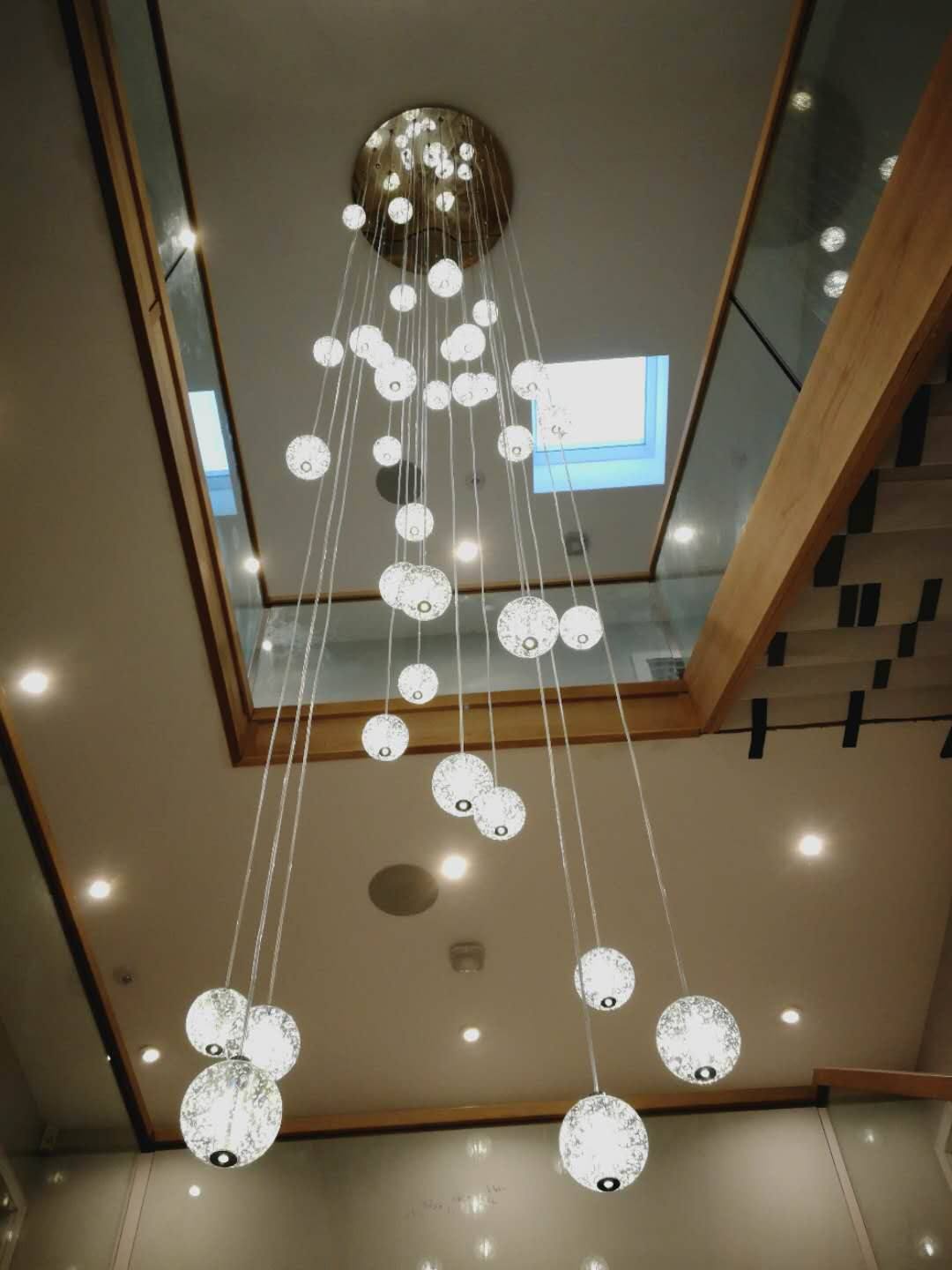 Cascade of glass sphere pendant lights in a double-height stairwell