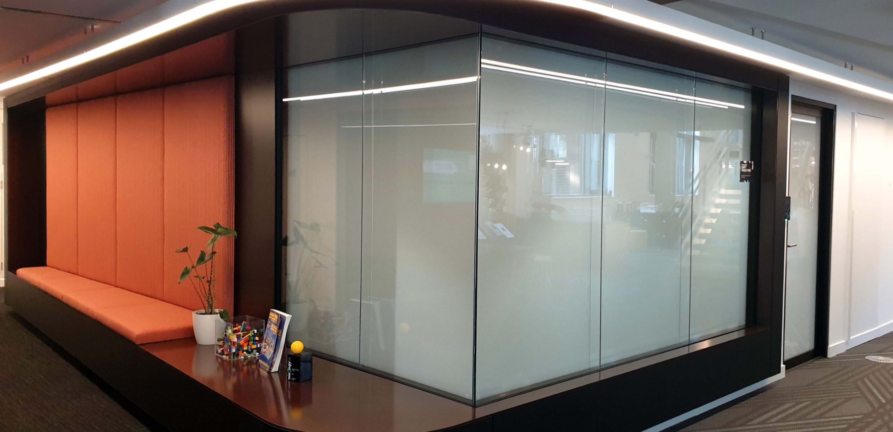 Frosted smart glass meeting room in an office with orange seating