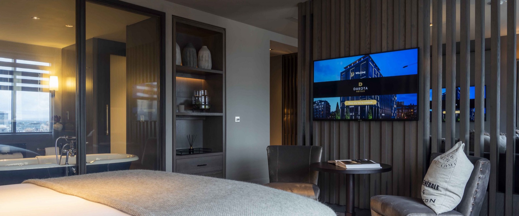 Hotel suite with a glass partition between the bedroom and an en-suite bathroom